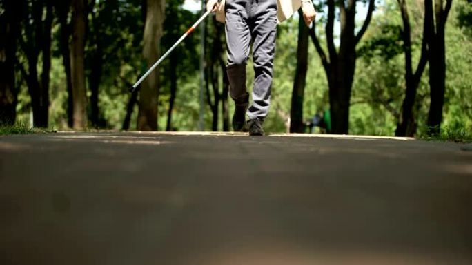 盲人在公园行走，用长手杖扫视道路，寻找障碍，定位