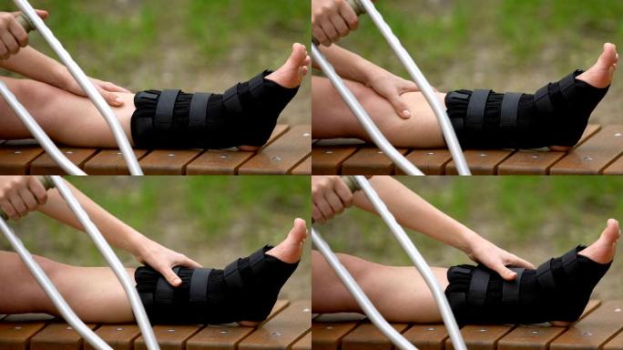 女拐杖患者在户外用步行支架按摩疼痛的腿
