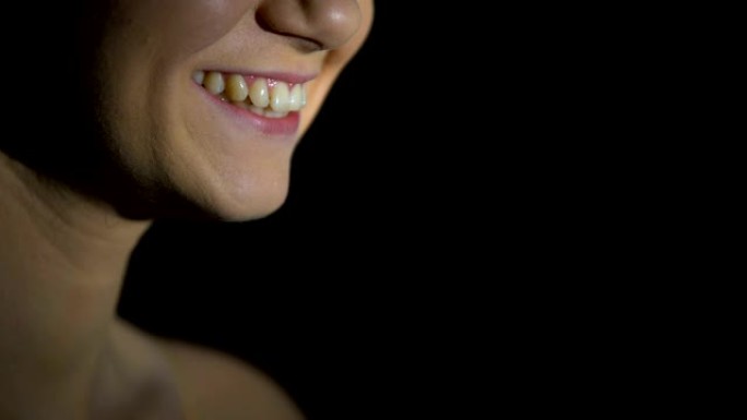 在黑暗的背景下微笑的女人，牙科服务，治疗