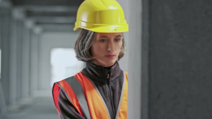 高加索女性建筑工人用附带的激光测量仪测量水平的墙壁