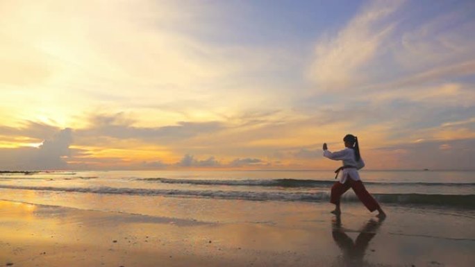 高清超慢动作: 日落时间在海滩上户外练习武术的年轻女性