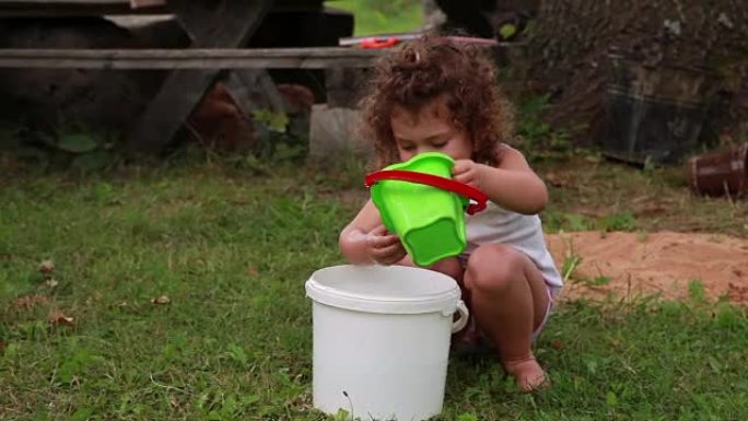 孩子从水桶里倒水到水桶里