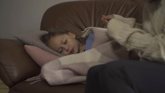 生病的高加索女孩躺在家里的毯子下的特写镜头。悲伤的孩子有发热。