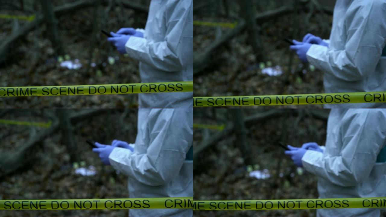 犯罪实验室的现场工作人员在森林里的犯罪现场输入平板电脑数据