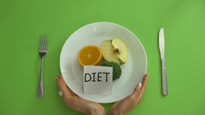 饮食注意事项与水果和蔬菜的盘子，双手用卷尺绑住