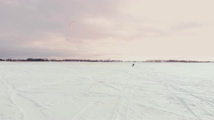冬天在滑雪板或滑雪板上进行风筝冲浪。在风中冰上滑冰。美丽的彩色帆