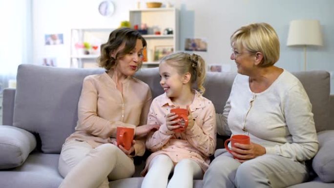 女性家庭成员坐在家里的沙发上聊天，一起喝茶