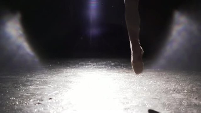 美丽的年轻芭蕾舞演员在工作室的黑色背景上聚光灯下的脚尖鞋。美丽苗条的芭蕾舞演员身材。