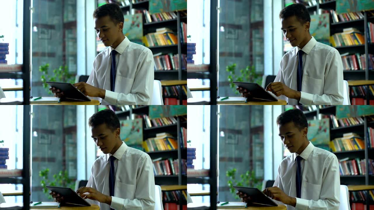 极客混血男学生在图书馆使用平板电脑在线做作业
