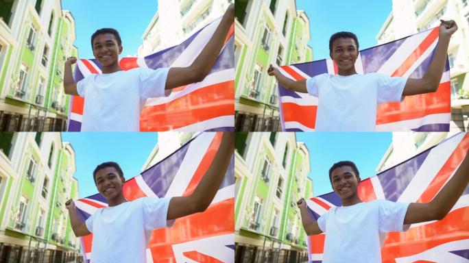 快乐的混血年轻人挥舞着英国国旗，微笑着，国定假日