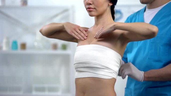 专业整形外科医生包裹胸部按压女性患者，健康