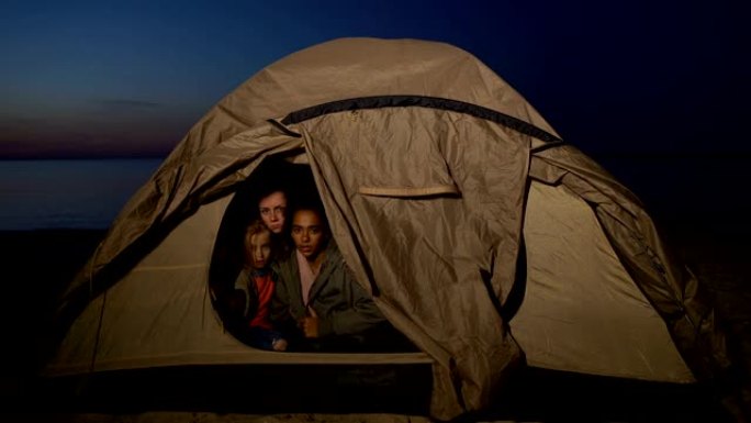 难民家庭坐在帐篷里，躲避岸边的移民边境服务