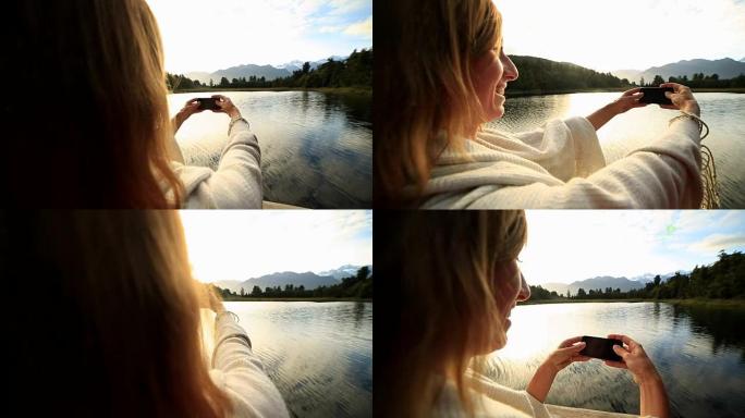 女人用手机拍摄山湖景观