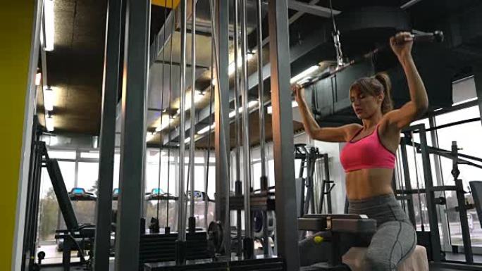 年轻的运动女子在健身房的健身器上进行运动训练。