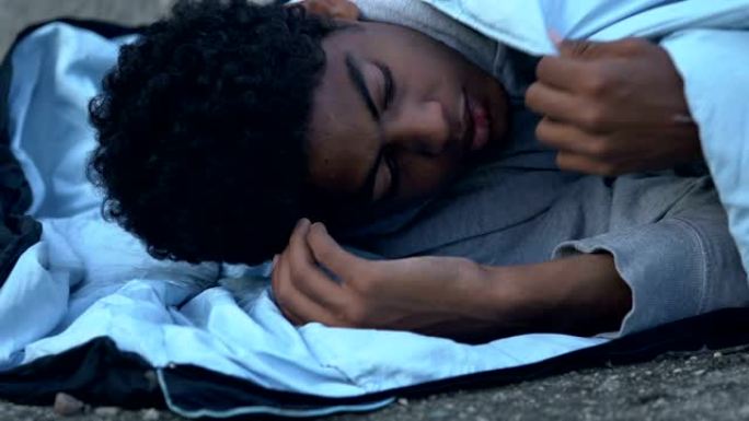 冻结的非裔美国难民躺在街上的睡袋中，绝望