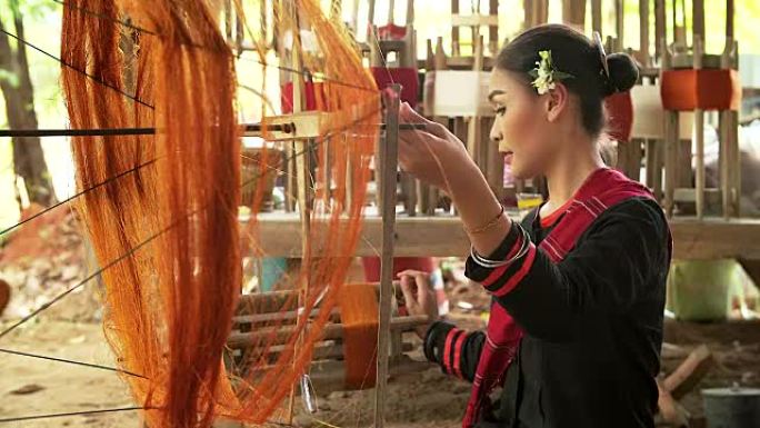 美丽的亚洲女人正在用传统工具编织棉花。