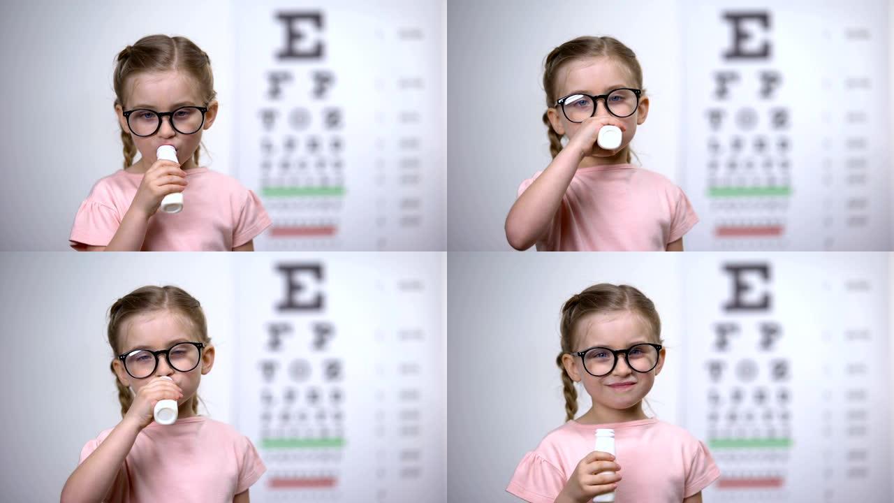 欢快的孩子在眼镜中喝美味的维生素糖浆以改善视力