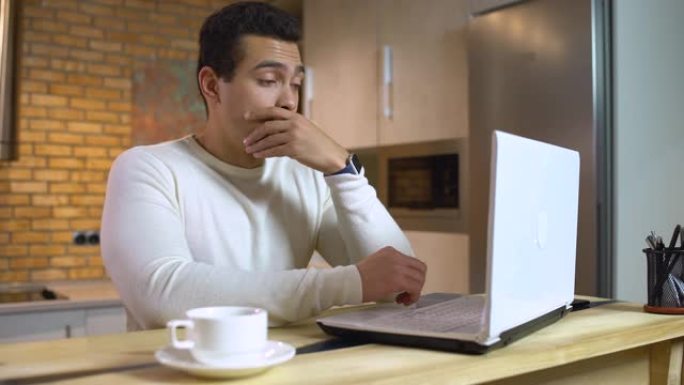 昏昏欲睡的阿拉伯男性在笔记本电脑上工作，感到疲倦，精力不足，疲惫