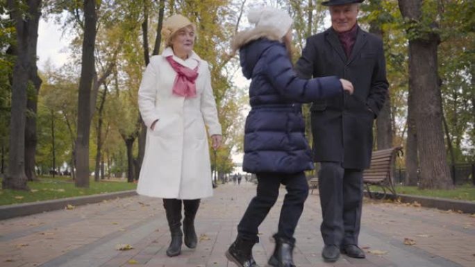 戴着白帽子的白人女孩和她的祖父母漫步，向前跑