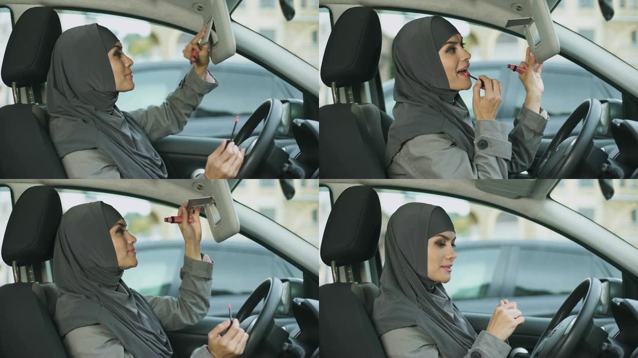 有吸引力的自信的穆斯林女士涂口红坐在车里，卖弄风情