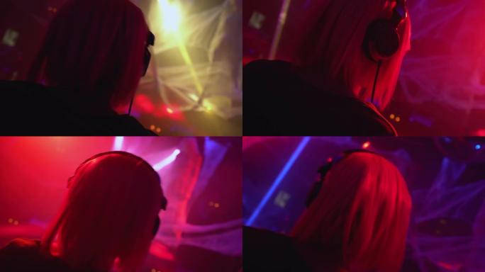 戴着耳机的女dj在夜总会工作，在派对灯光下随着音乐跳舞
