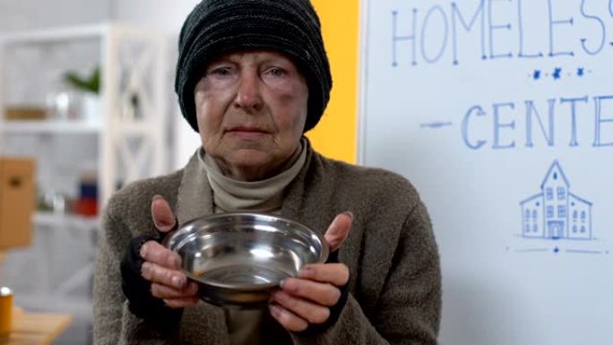沮丧的饥饿无家可归的女性向镜头展示空盘子，贫穷
