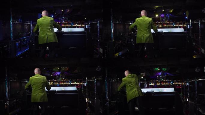 穿着绿色夹克的白人老人混合音乐和舞蹈的后视图。在夜总会工作的成熟男性DJ。活跃的老年人，生活方式，娱