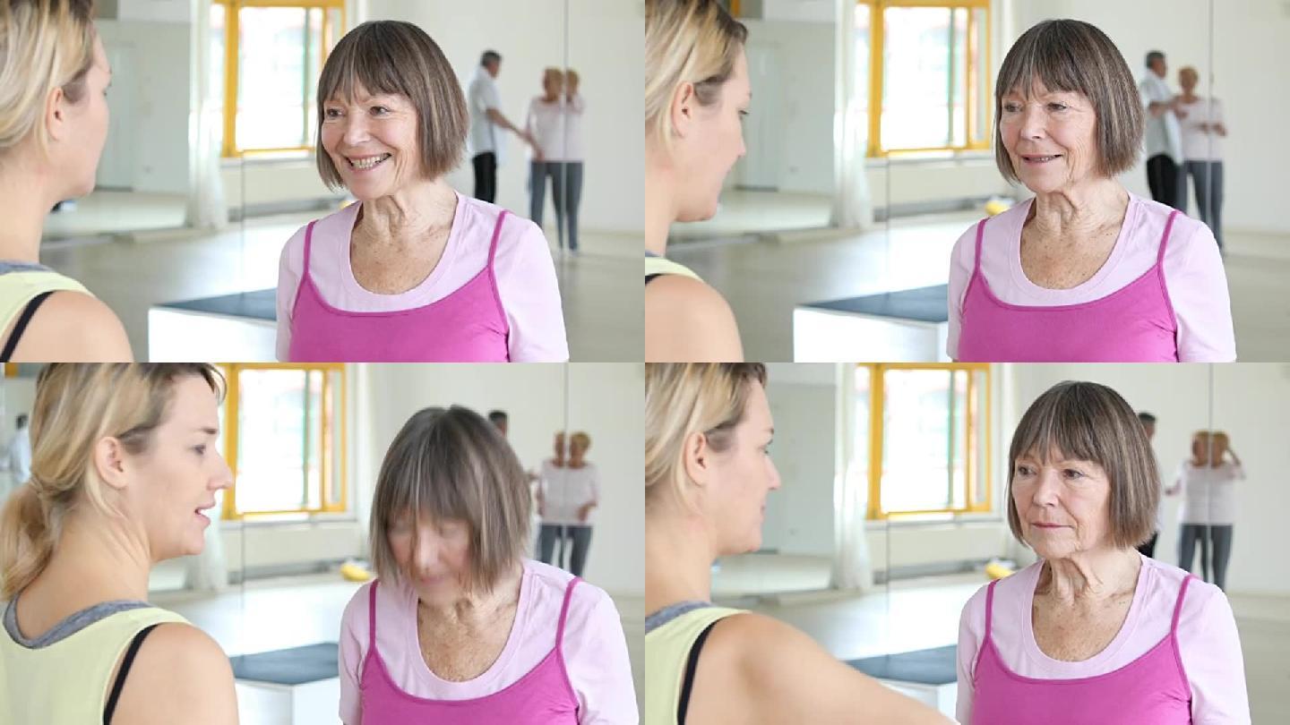 高级女性在健身房与瑜伽教练交谈
