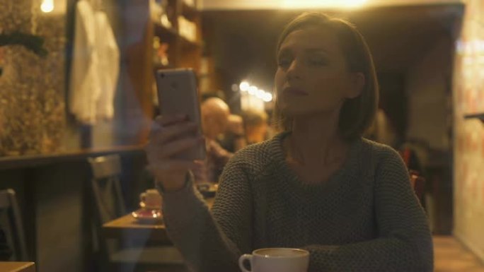 年轻女子在智能手机上聊天，坐在舒适的咖啡馆里，免费无线网络