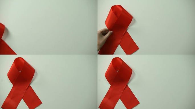女性手把红丝带放在桌上，艾滋病意识和预防，健康