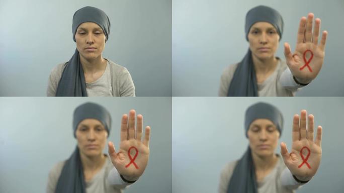 红丝带标志在妇女的手掌上显示停止的手势，艾滋病宣传活动