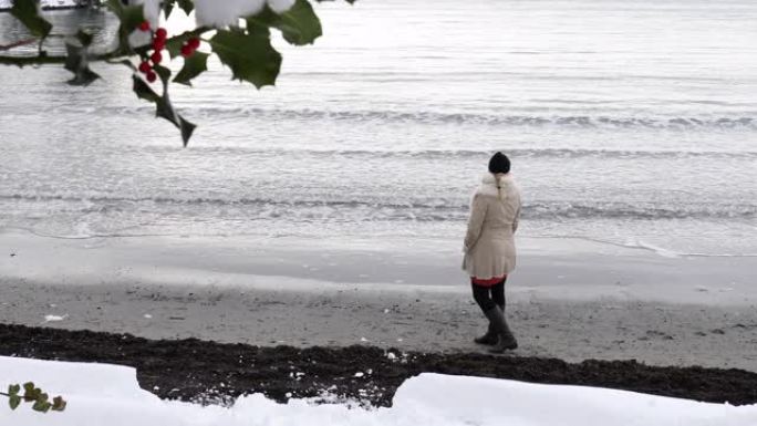 成熟的女人在冬天沿着海滩散步