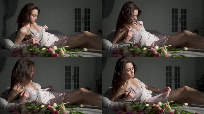 可爱的热女孩在睡衣躺在床上的郁金香和享受她的身体。