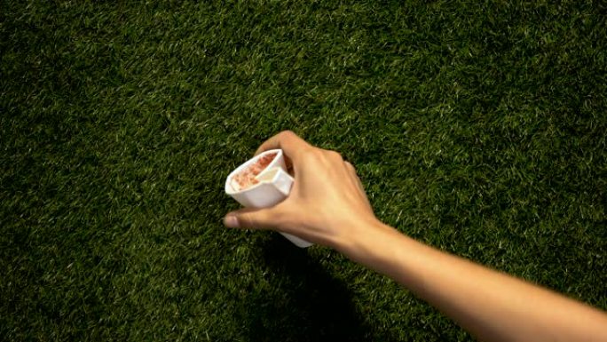 女人手扔用过的纸杯在草地上一次性餐具过度消费