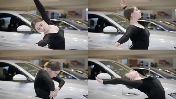 高加索芭蕾舞女演员的侧视图向后弯曲并离开镜头。专业女芭蕾舞演员在汽车陈列室跳舞。汽车工业，优雅，美丽