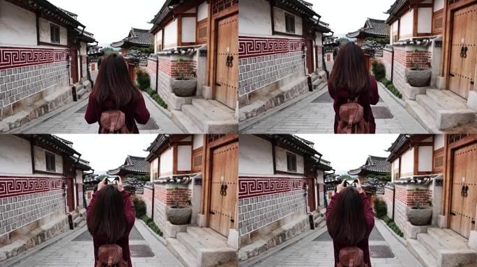 年轻女子旅行者用智能手机拍照，然后前往韩国首尔市的北村韩屋村