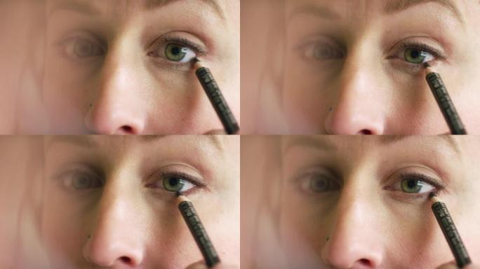 三十多岁的白人妇女在化妆时用眼线笔画眼睛