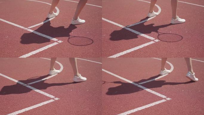 穿着白色运动鞋的女人的腿在球场上打网球前做热身。