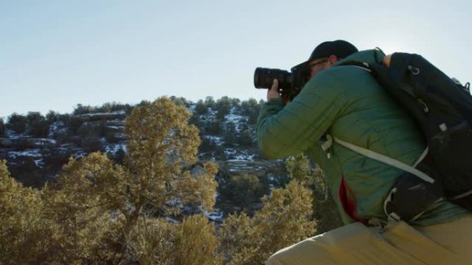 一位四十多岁的白人男性摄影师穿着远足装备，冬天在科罗拉多州西部的高沙漠中拍照 (科罗拉多州国家纪念碑