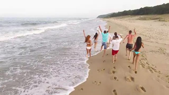 一群年轻人在沙滩上奔跑的4k后视图