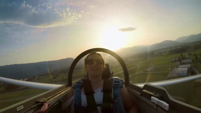 滑翔机乘客座位上的LD年轻女子在日落时享受飞机低空滑行