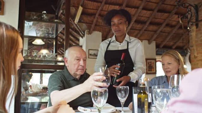 侍酒师倒酒给祖父在家庭用餐时品尝的慢动作镜头