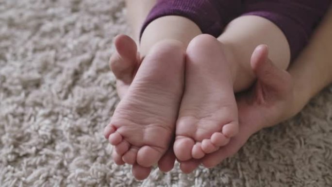 小高加索婴儿的脚被女性手抓住的特写镜头。温柔，母性的快乐，幸福，生活方式。电影院4k ProRes总