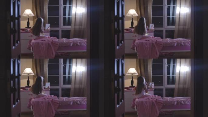 白人女学生坐在粉红色的床上洗完妆。可爱的长发孩子准备晚上在她的房间里睡觉。青春期，童年，休息。电影院