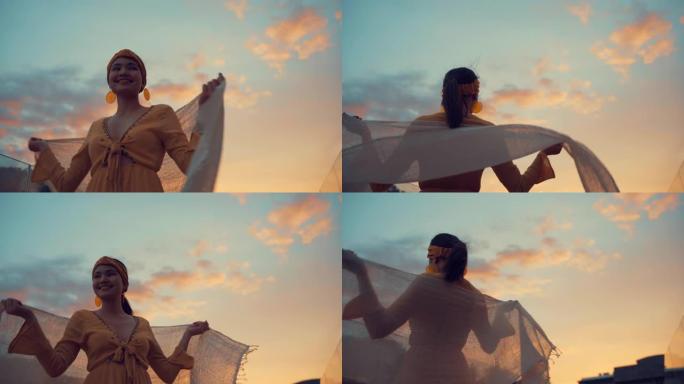4k镜头美丽的女人在黄昏时在风中拿着白色织物。