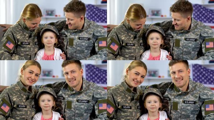 男女士兵拥抱着戴军帽的女儿，对着镜头微笑