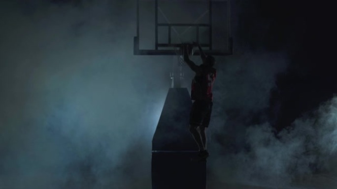 健康的年轻人在黑色背景下打篮球，烟云密布。