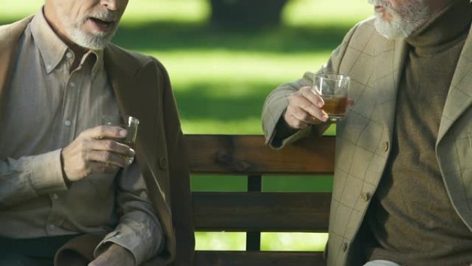 年老的成功商人享受精英威士忌口味，坐在外面休息