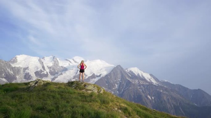 女人站在山顶上，在日落时望着勃朗峰