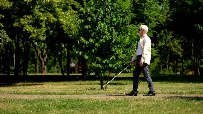 盲人养老金领取者使用白色拐杖安全导航，在公园独立行走